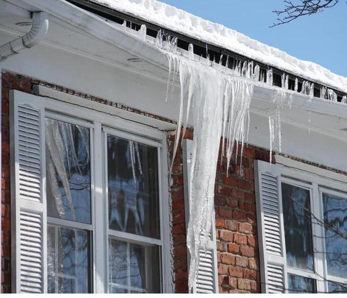 A close up of an ice dam hanging off of a building